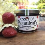 Strawberry and elderflower conserve jar displayed with fresh strawberries and elderflowers